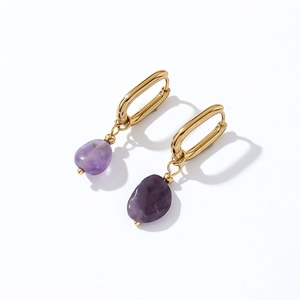 Detailed macro view of natural purple amethyst pendants on gold-plated metal earring hoops