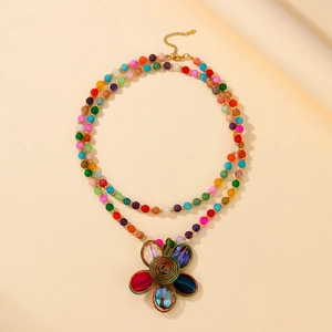 Detail of colorful beads and handcrafted aluminum wire floral pendant on a layered necklace