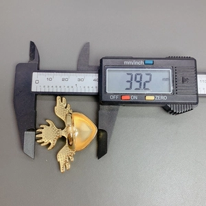 Macro shot of gold heart wing ring being measured with a digital caliper for 39.2 mm size