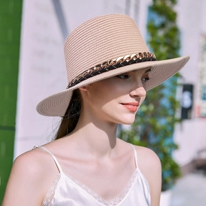 Detail of beige straw hat with metal chain decoration and black woven band for summer sun