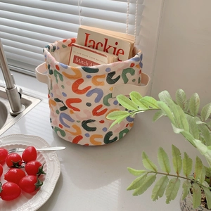 Top view of a round fabric storage basket featuring colorful graffiti patterns and handles