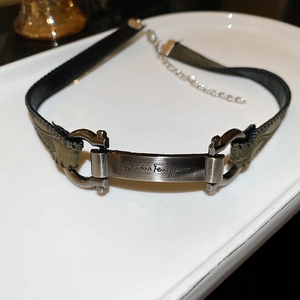Detailed macro view of green leather choker with bronze metal brand plaque and buckle