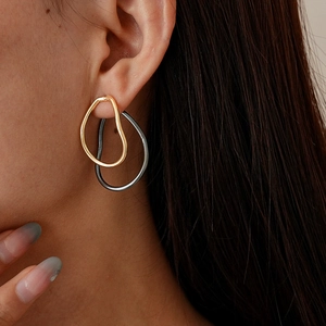 Close-up of two-tone irregular teardrop earrings in polished gold and silver metal
