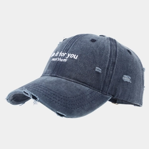 Detail of distressed dark grey baseball cap with white slogan embroidery and frayed edges