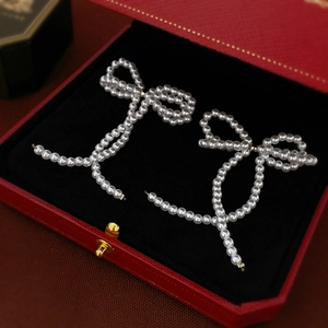 Elegant white pearl bow earrings with tassel details displayed in a premium jewelry box