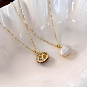 Close-up of golden heart and white spiral pendants on fine necklaces in a shell bowl
