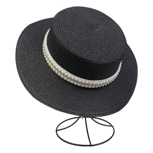 Detail of black flat top straw hat featuring double row pearl and gold chain trim