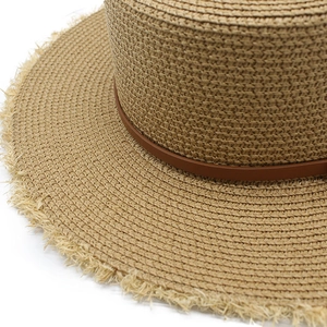 Détail du chapeau de paille à bord frangé avec une sangle en cuir marron élégante