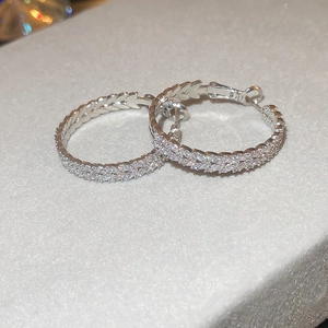 Macro view of silver hoop earrings featuring marquise leaf patterns with micro-set zircons