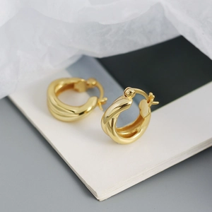 Close-up of golden twisted hoop earrings with a polished finish and secure mechanical clasp
