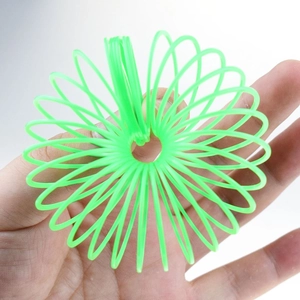 Close-up of bright green plastic slinky toy with elastic spiral structure held by hand