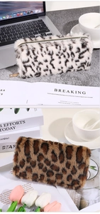 Detailed view of plush leopard print pouches in white and brown with gold zippers