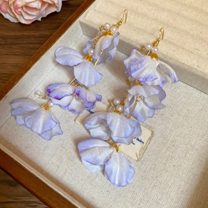 Détail macro de boucles d'oreilles fleurs en tissu violet avec perles et pompons