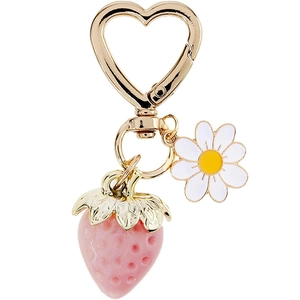 Detail of strawberry and daisy pendants with a golden heart-shaped keychain clasp
