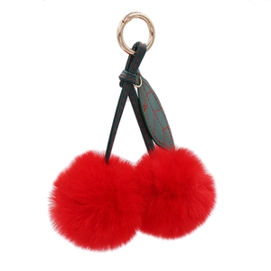 Plush cherry keychain with red pom-poms and green leaves on gold spring ring