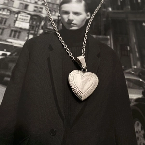 Close-up of vintage engraved heart locket pendant necklace in silver stainless steel finish