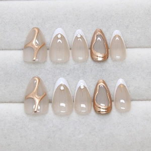 Short almond press-on nails with white French tips, gold 3D lines, and sparkling rhinestones