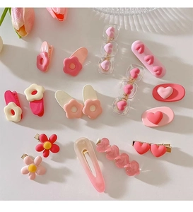 Flat lay of pink Y2K style children's hair clips in various flower and heart shapes