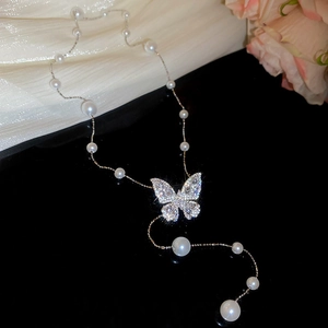Macro view of butterfly pendant with micro-paved zircons and elegant pearls on silver chain