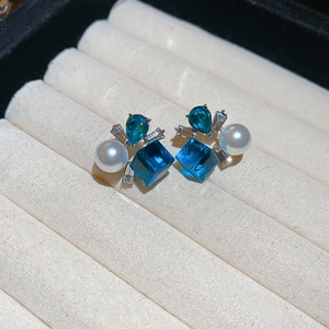 Detailed macro shot of blue crystal flower earrings with pearls on a velvet jewelry tray