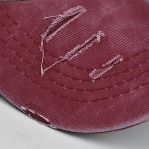 Close-up of distressed details and frayed holes on a washed denim baseball cap