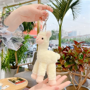 Detailed close-up of a white alpaca plush keychain with soft fur and metal ring