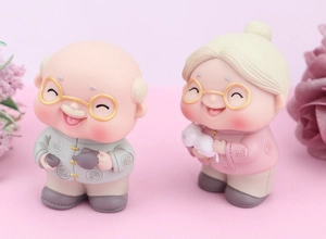 Close-up of cute cartoon elderly couple figurines with a small cat for cake decoration