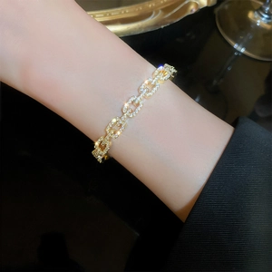 Detailed close-up of a gold-plated chain bracelet set with sparkling zircon crystals