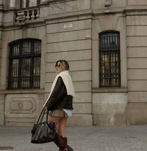 Vista street style di una minigonna a pieghe a quadri marroni con stivali alti