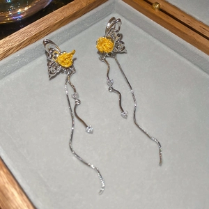 Dettaglio di orecchini a farfalla con zirconi e nappe d'argento in una scatola regalo