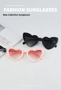 Dettaglio di occhiali da sole a cuore neri e rosa sfumati su una rivista di moda