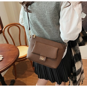 Gros plan d'un sac plissé marron café avec fermoir rotatif doré élégant et bandoulière fine