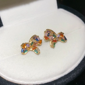 Detail of gold puppy stud earrings set with colorful baguette-cut rainbow gemstones