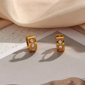 Detailed close-up of 18K gold-plated square hoop earrings with three clear zircon stones