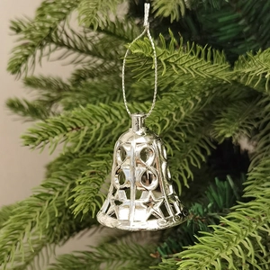 Nahaufnahme silberner Glocken mit Sternenausschnitt am grünen Weihnachtsbaum
