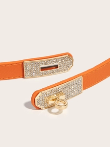 Detail of orange cross-grain leather belt with a gold rhinestone turn-lock buckle