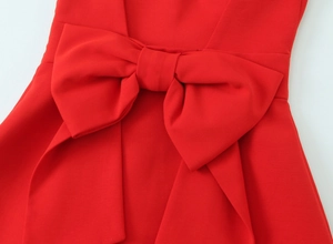 Close-up of a large red bow detail on a stretchy dress showing the fabric texture