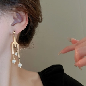Elegant geometric gold drop earrings with pearls on model in minimalist style