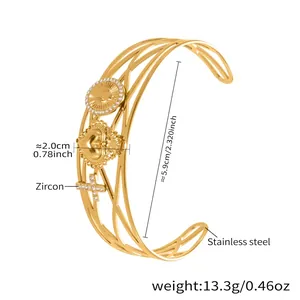 Détail du bracelet en acier doré avec breloques croix et cœur serties de zircons