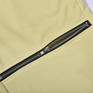 Detailed macro view of a silver metal zipper on beige woven fabric pants pocket