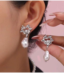 Close-up of vintage heart pearl drop earrings featuring silver flower design on a model