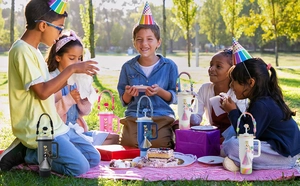 Outdoor picnic scene with colorful tumblers featuring handmade daisy charms and lanyards