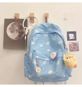 Detail of light blue backpack with white bear prints and cute plush charms attached