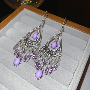 Detailed macro view of purple teardrop tassel earrings with silver crystal settings