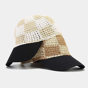 Handcrafted checkered straw baseball cap and black sun hat stacked on a gray surface