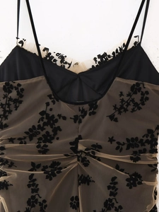 Détail d'une robe en maille beige avec motifs floraux noirs et fines bretelles réglables