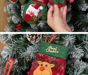 Detail of Christmas stocking and glove ornaments with snowman and elk motifs on a tree