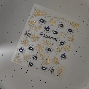 Detail of Halloween nail stickers with golden spider webs and black cartoon spider patterns