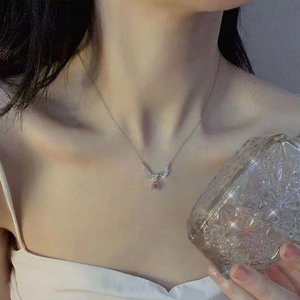Close-up of the angel wing necklace with a teardrop purple gemstone worn by a female model