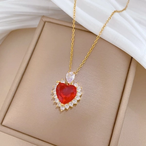 Close-up of heart-shaped red zircon pendant with diamond halo on gold chain in gift box